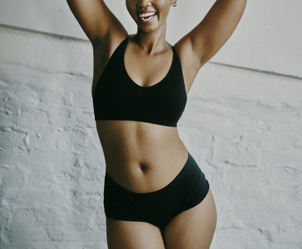 Black woman with a black bra and underwear with her arms over her head