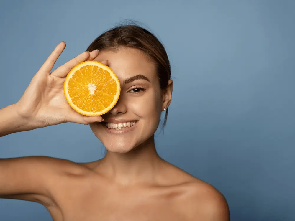 woman holding a slice of orange in front of her
